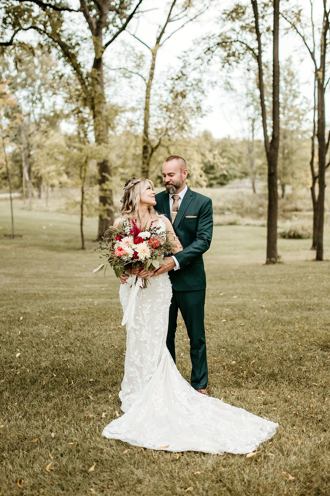 Bride and groom embrace in a sunlit meadow